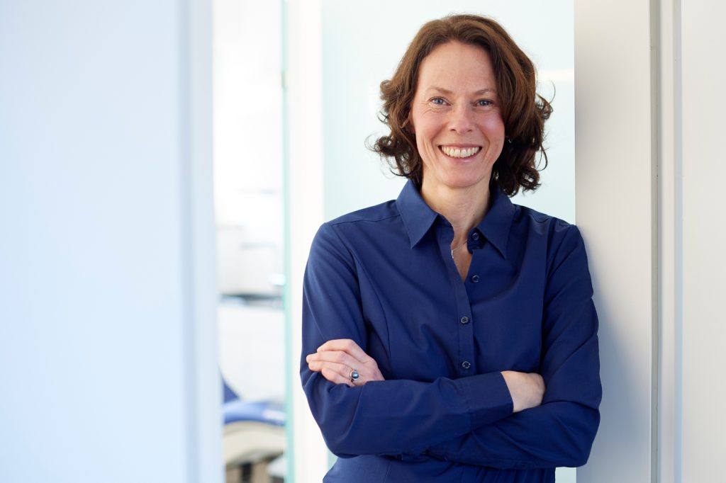 Ehefrau und Praxismanagerin Anita Hoffmann lehnt an der Tür und blick sympathisch in die Kamera